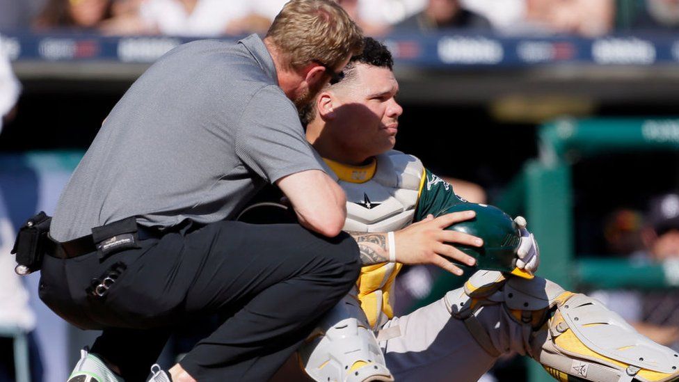 Bruce Maxwell is attended to by a trainer after getting hit with a ball on 20 September