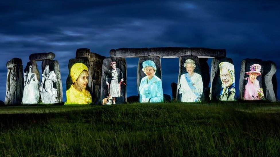 Stone Henge with images of the Queen pictured on the stone face.