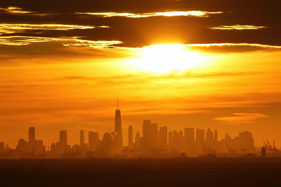 The sun rises behind lower Manhattan and One World Trade Center in New York City, US, 20 August