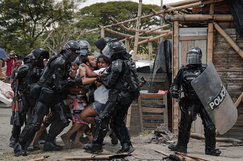 Police agents arrest a man while his wife and family resist, during evictions of people from the San Isidro settlement, in Puerto Caldas, Risaralda, Colombia, on 6 March 2021