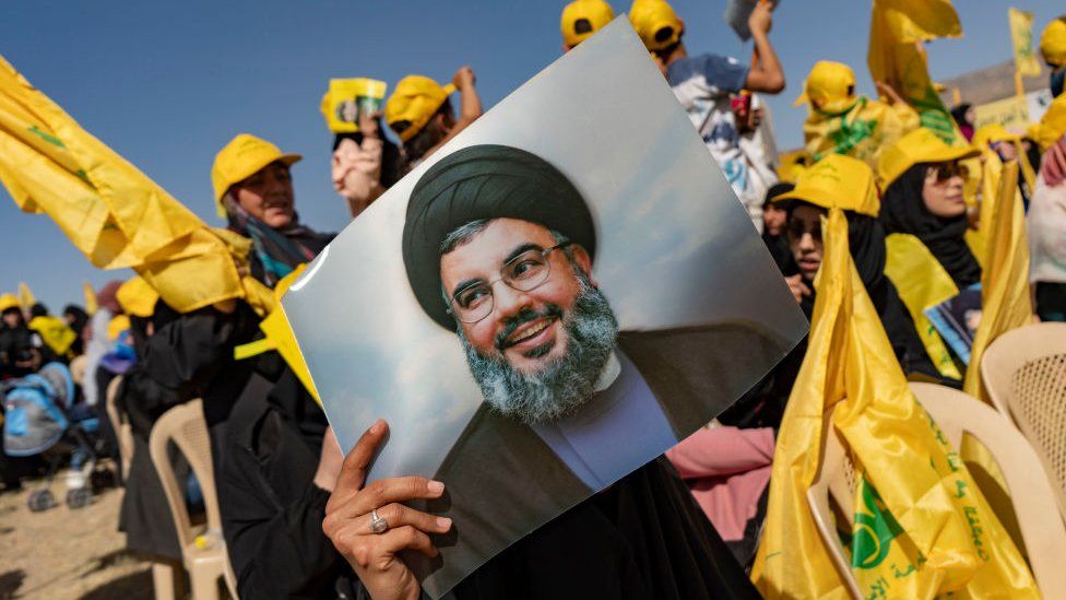 A woman holds a photo of Hassan Nasrallah