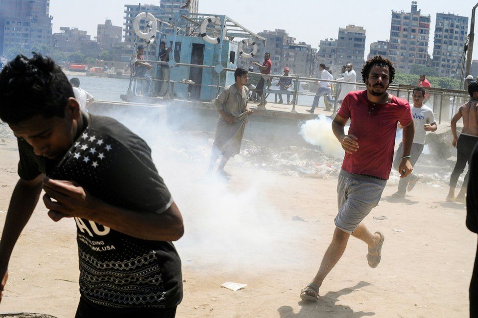 People run for cover from tear gas on the Nile island of al-Warraq, 16 July