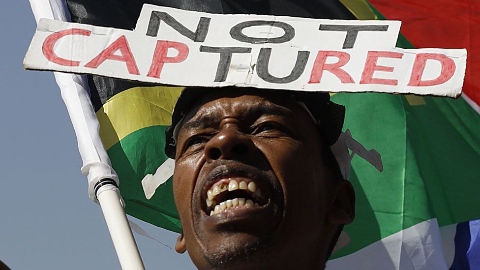 A supporter of the Organisation Undoing Tax Abuse (Outa) holds a South African flag while picketing outside Raymond Zondos judicial commission of inquiry into state capture at Parktown on August 20, 2018 in Johannesburg, South Africa.