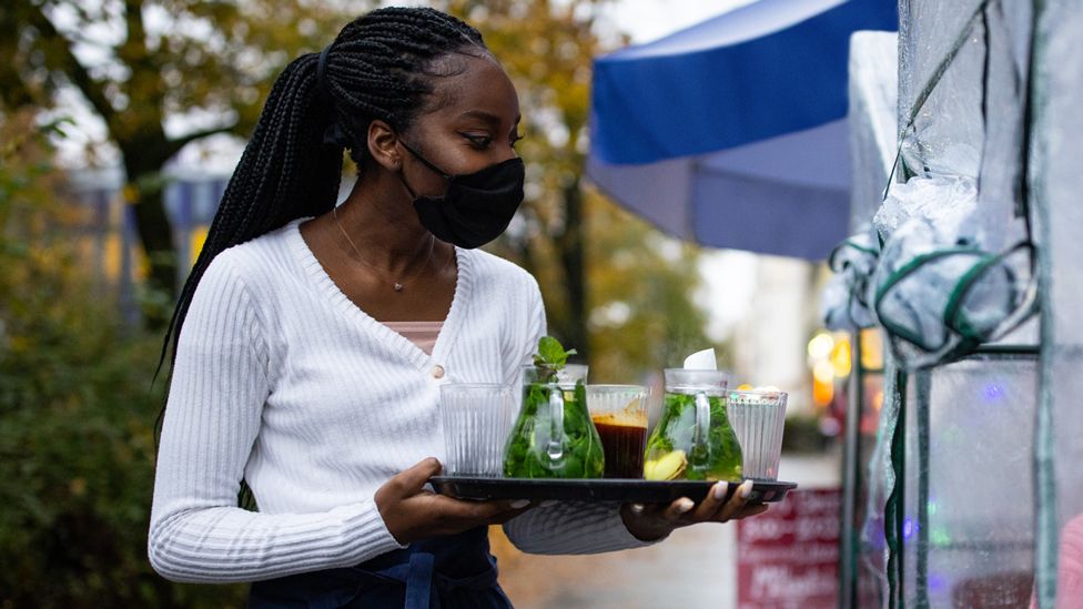 Waitress in mask serving drinks