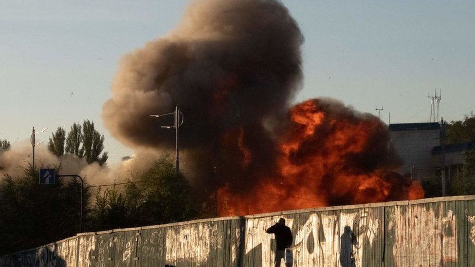 A man falls to the ground as a drone attacks a building in Kyiv,