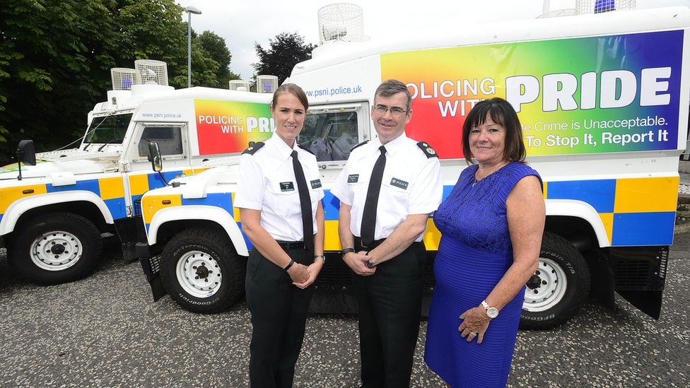 Police officers stand with 'Pride' Land Rovers