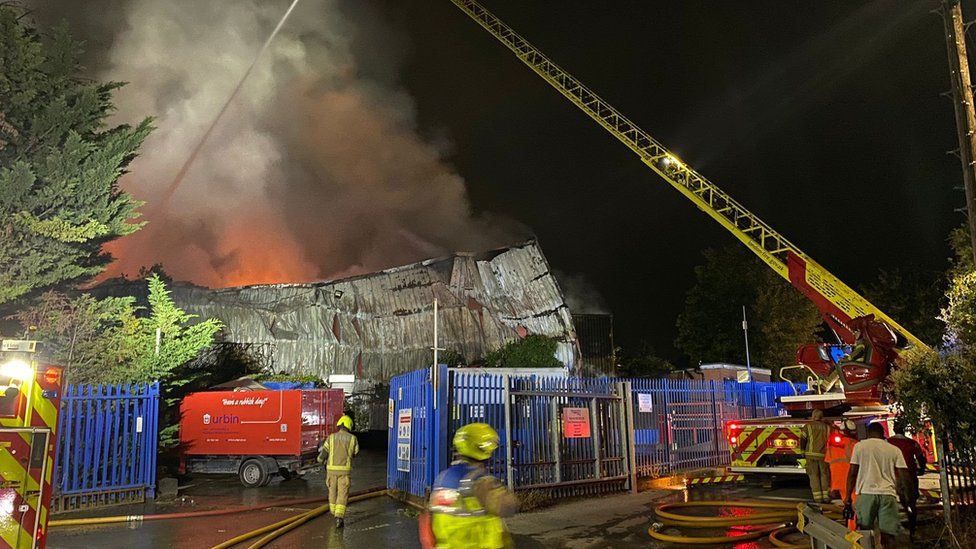 Image showing a ladder and water jet over flames behind the partially-collapsed building.