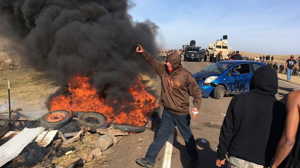 Demonstrators stand next to burning tires as armed soldiers and law enforcement officers assemble on Thursday, Oct. 27, 2016
