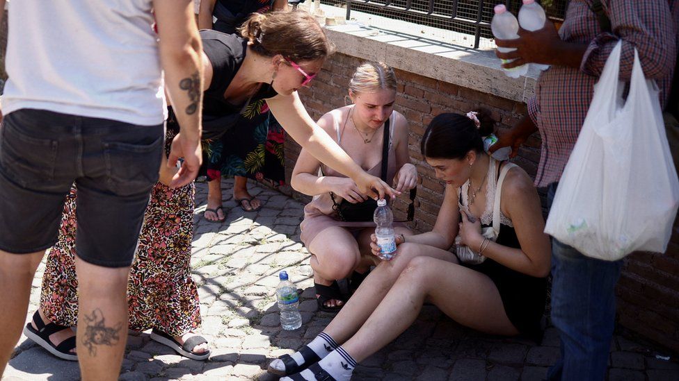 A tourist from the UK receives help near the Colosseum after fainting during the heatwave in Rome