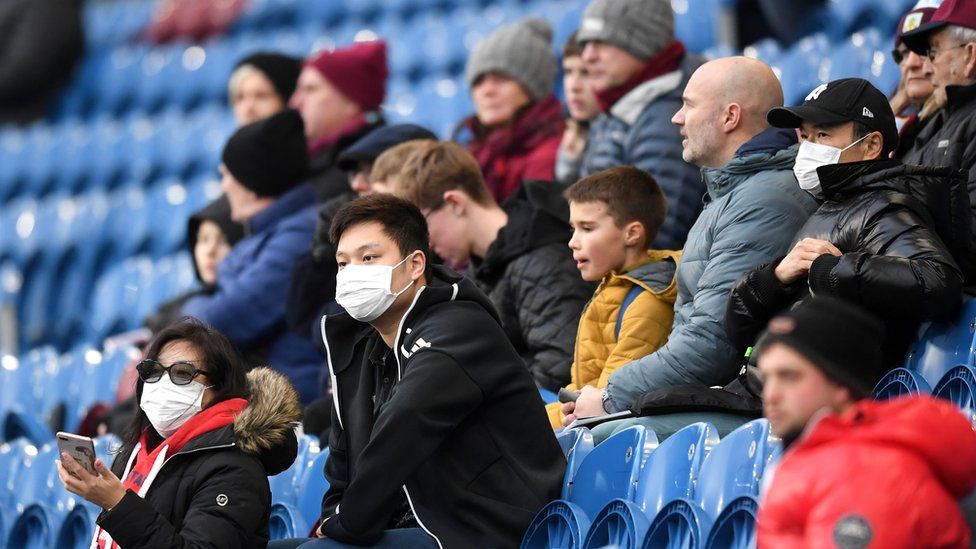 Fans wear disposable face masks prior to the Premier League match between Burnley and Tottenham at Turf Moor
