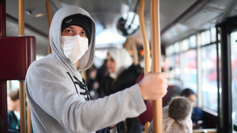 A man wearing a facemask on a bus in London
