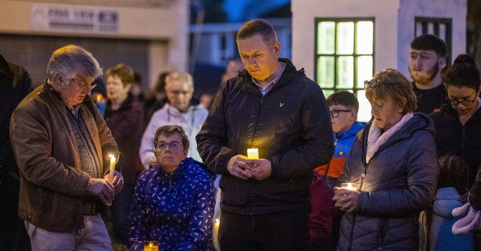 People hold candles during a vigil to remember the Creeslough disaster victims in Castlefin