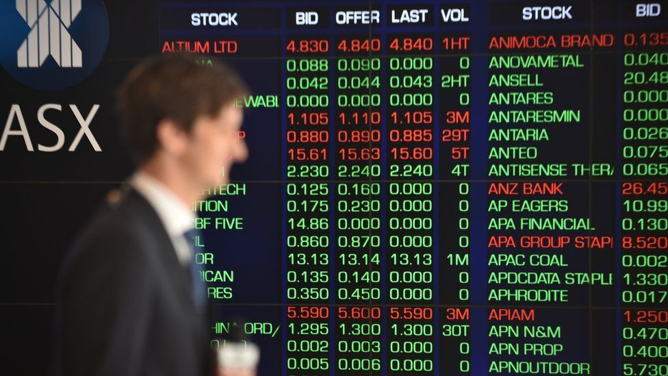 man walks past Australia stock exchange share board