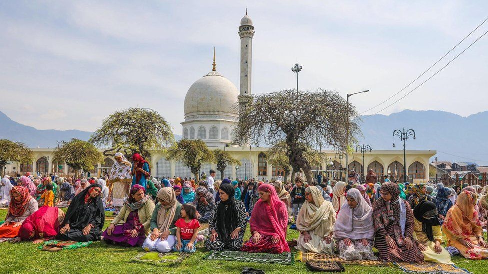 Women sitting on the grass with white dome in the background in Srinagar, Indian-administered Kashmir