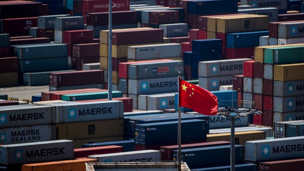 A Chinese flag is seen in front of containers at the Yangshan Deep-Water Port, an automated cargo wharf, in Shanghai on April 9, 2018.