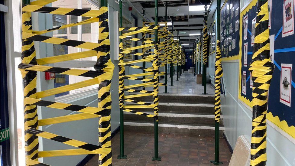 Support poles wrapped in hazard tape holding up the ceiling in the school corridor