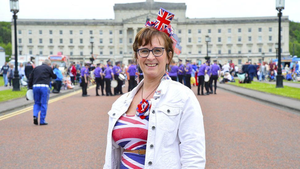 A woman dressed in a Union Jack dress and matching top hat headband outside Stormont
