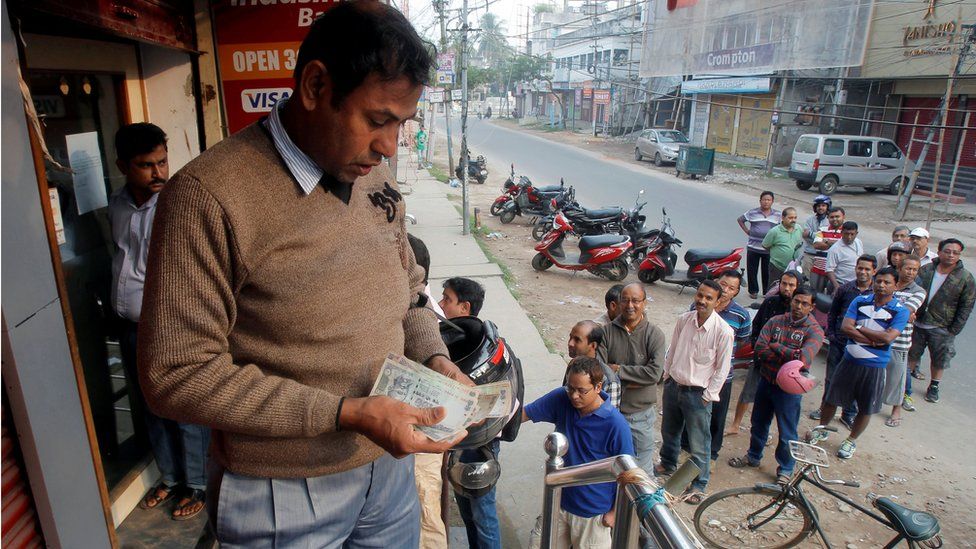 A man counts Indian rupee banknotes after withdrawing them from an ATM in Agartala, India,