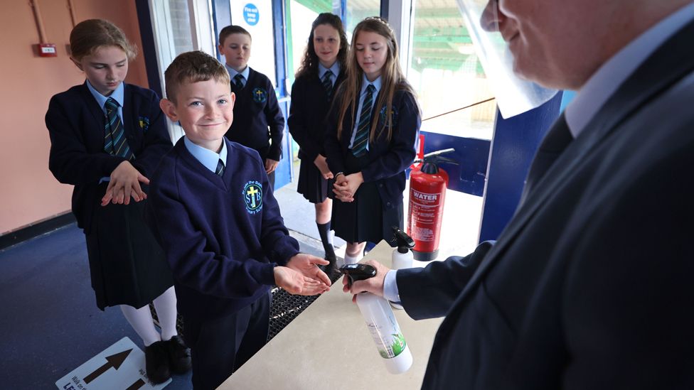 A principal in West Belfast uses sanitiser on pupils hands, as schools in Northern Ireland reopen to pupils following the coronavirus lockdown, 24 August 2020