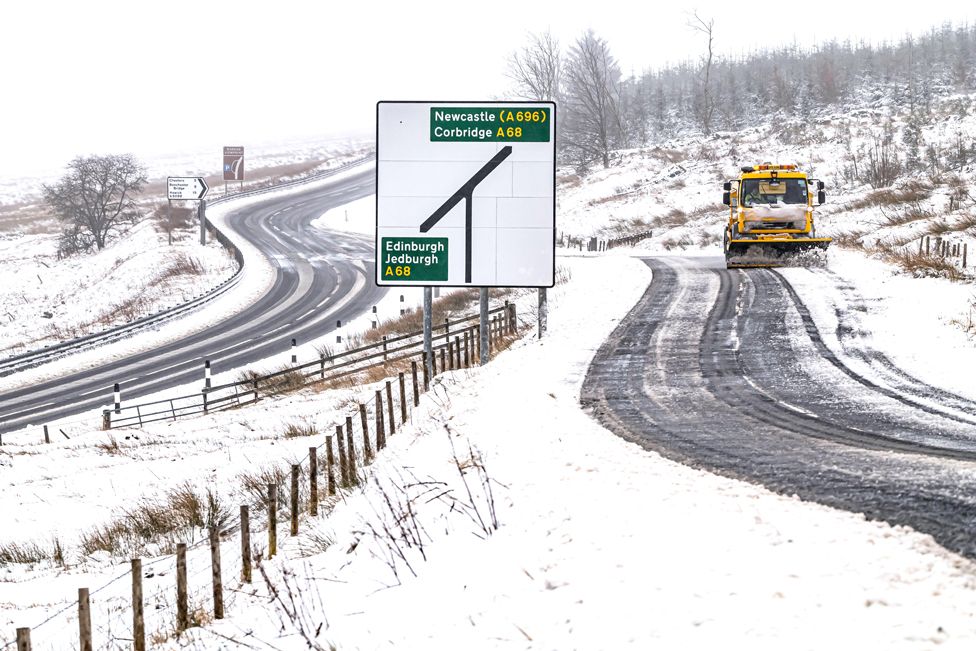 A snow plough works on a snow-covered road