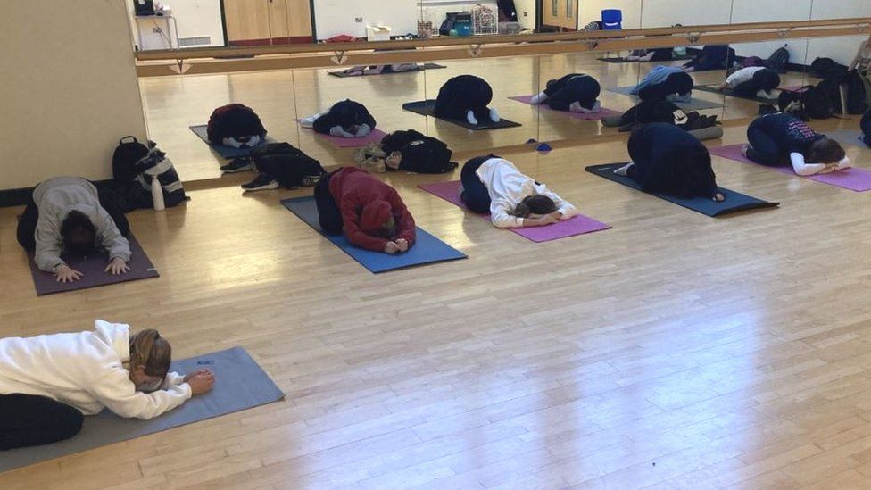 Yoga class members pose in child's pose on their mats in a studio