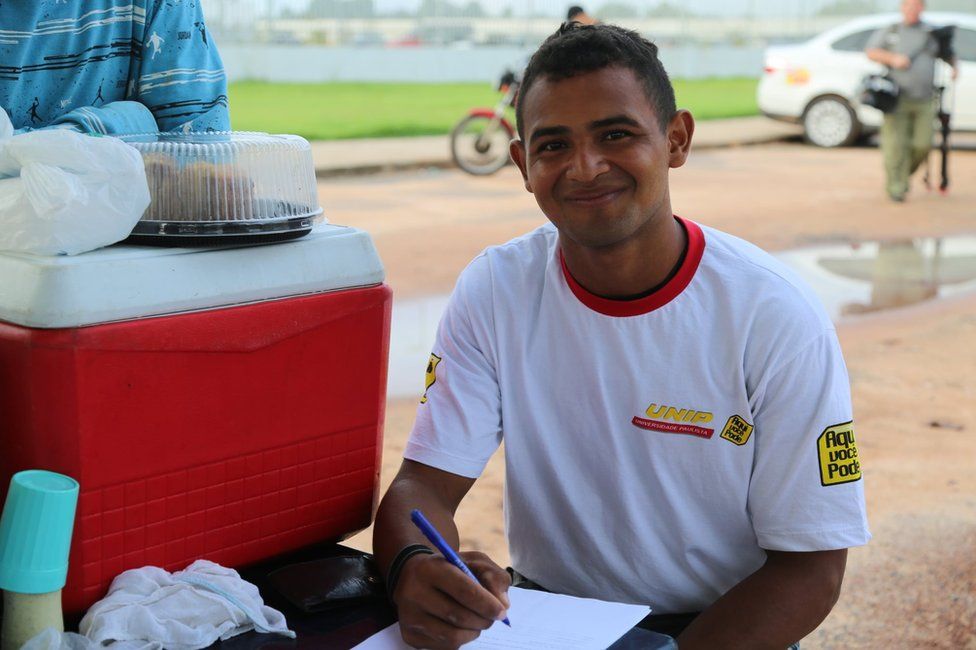 Jorge fills in a form outside the federal police station in Boa Vista