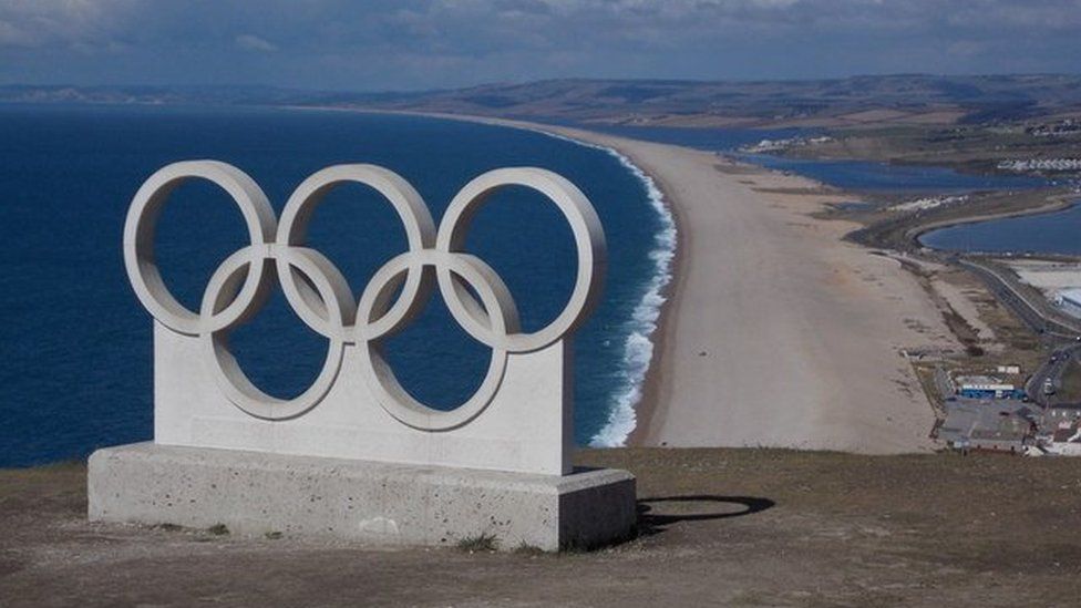 Large sculpture of the Olympic rings in Portland with Chesil Beach in the background.