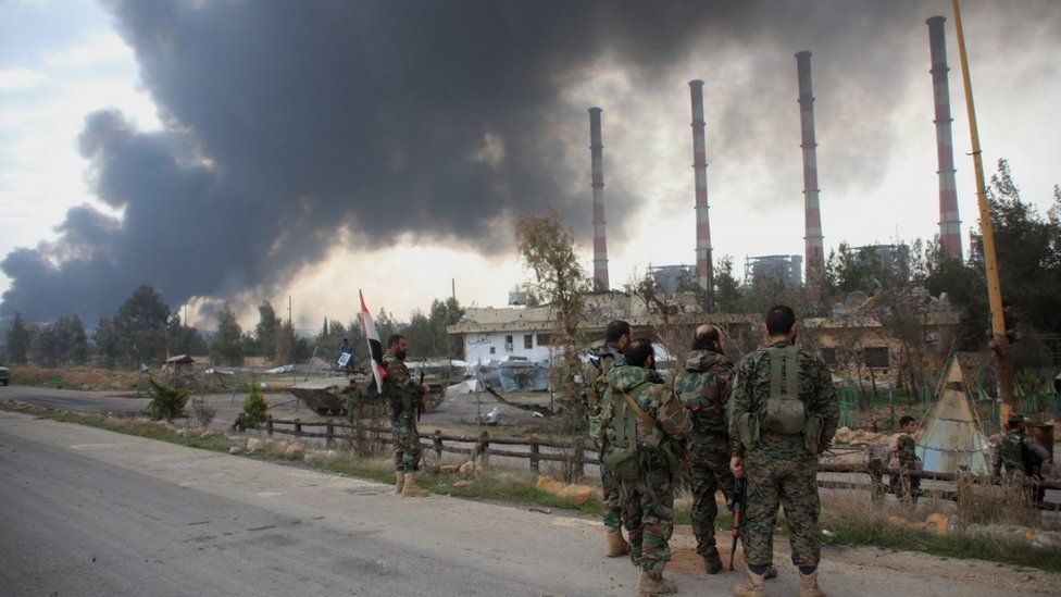 Syrian government forces look at smoke billowing from Aleppo"s thermal power plant after they took control of the area on the eastern outskirts of Syria"s northern embattled city from Islamic State (IS) group fighters on February 21, 2016