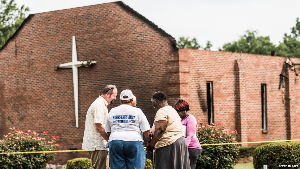 People pray near the burnt ruins of the Mt Zion AME Church in Greeleyville, South Carolina. Mt Zion was the seventh black church to burn in the southern US in less than two weeks