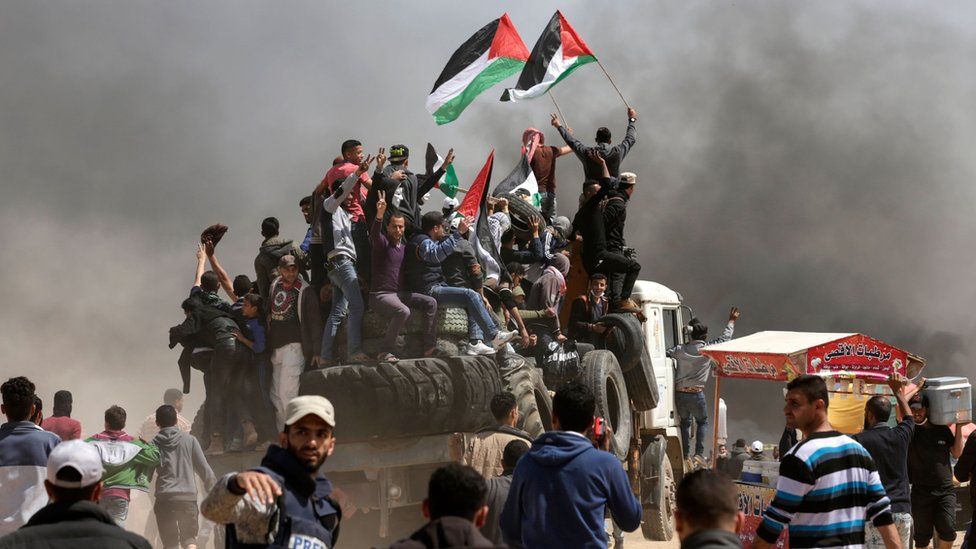 Palestinian men wave flags during a protest east of Gaza City on 6 April 2018