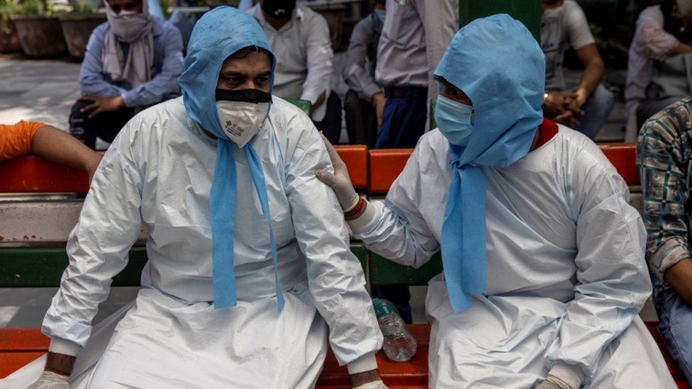 Two men sit together in PPE