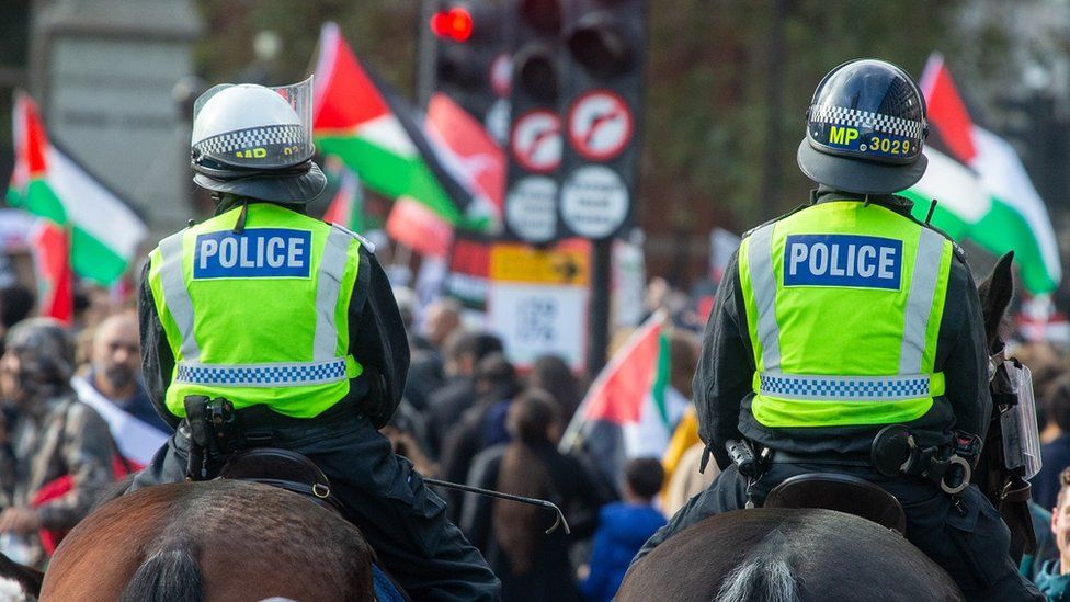 Two police officers on horseback seen from behind at a pro-Palestinian march