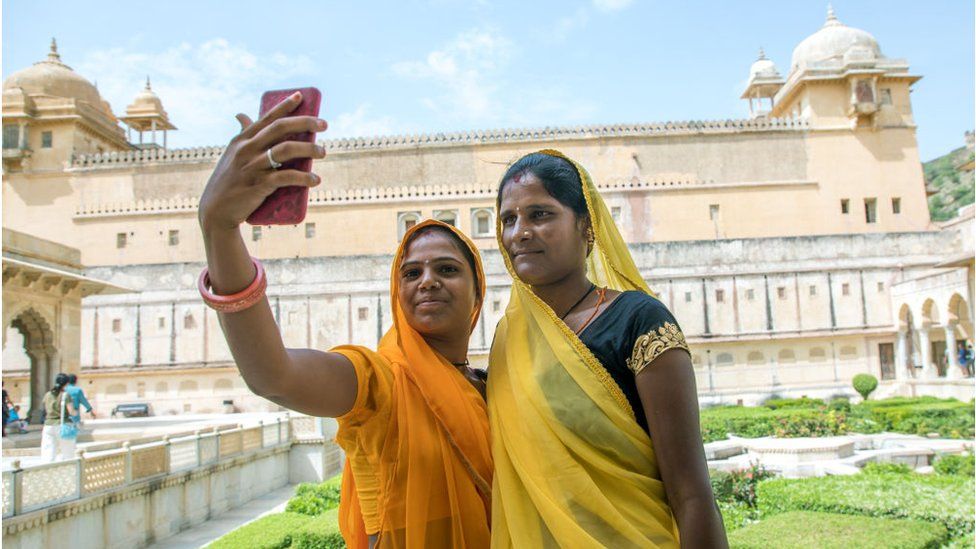 Women take a selfie in front of Amer fort and palace, India