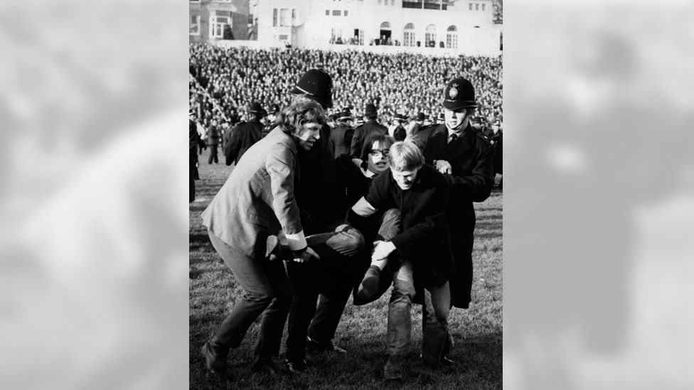 Protestor being carried off pitch