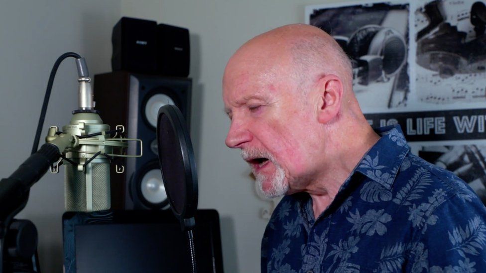Derick Davies singing on the microphone in his home music studio