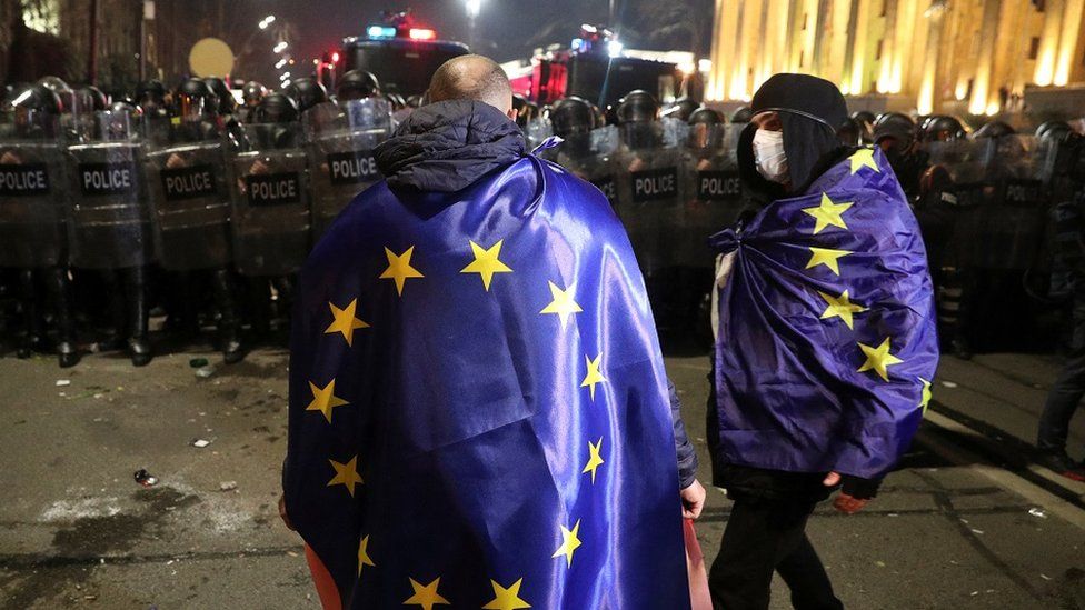 Протестующие, завернутые в флаги ЕС, проводят демонстрацию в центре Тбилиси