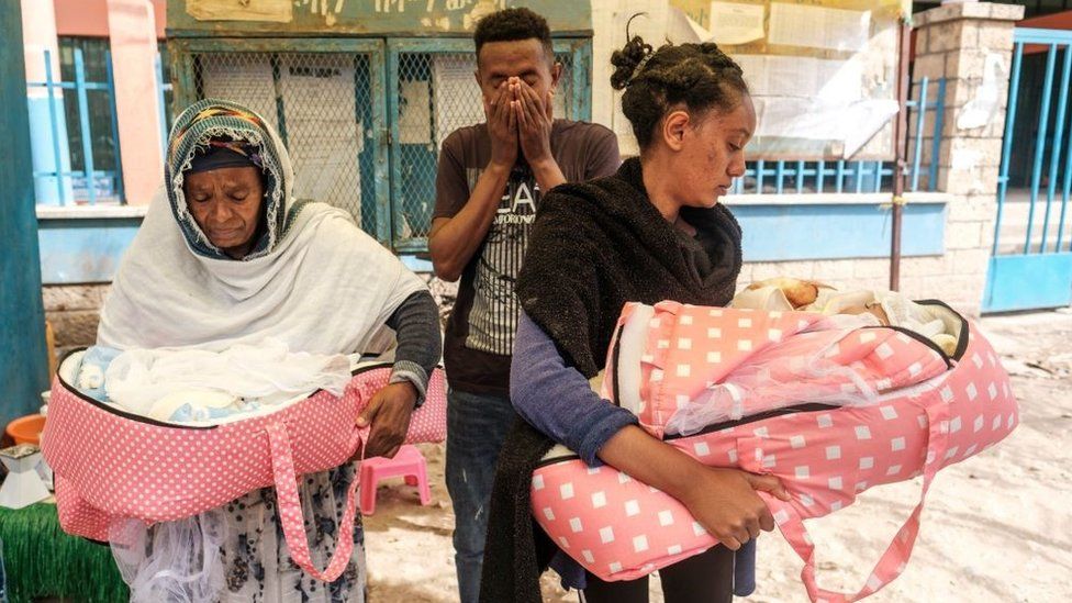 Elias Gebrekidan (C) stands next to members of his family who holds his twin nieces Tsion and Roda, 2 months old, who were born during the hostilities, in Wukro, north of Mekele, on March 1, 2021