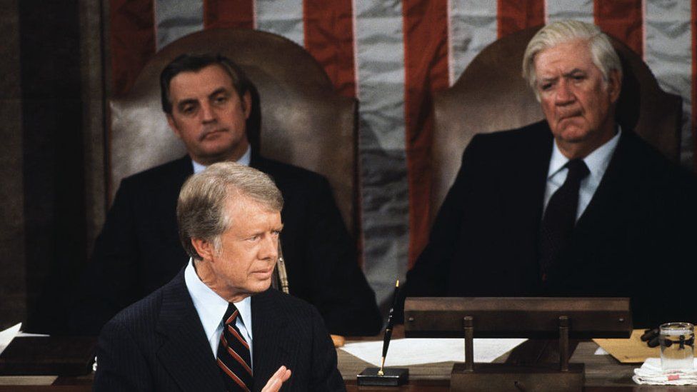 Speaker of the House "Tip" O'Neill watches as US President Jimmy Carter speaks