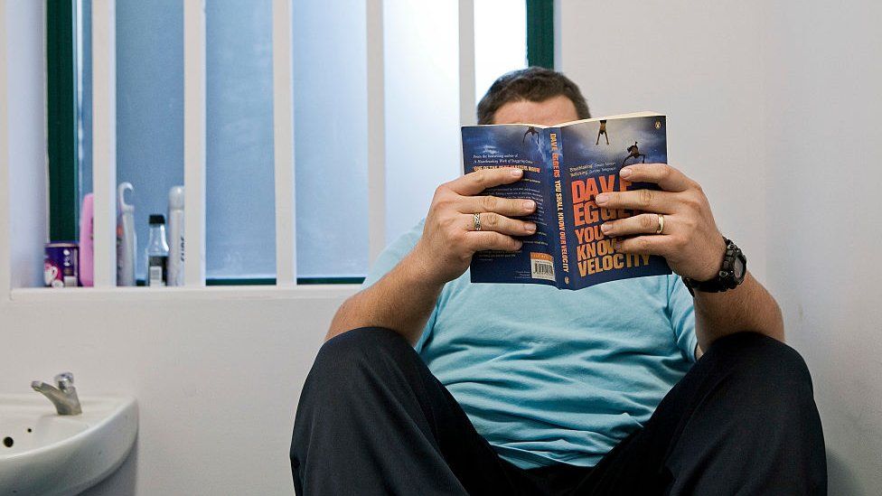 A prisoner reads a book in his cell at Wandsworth