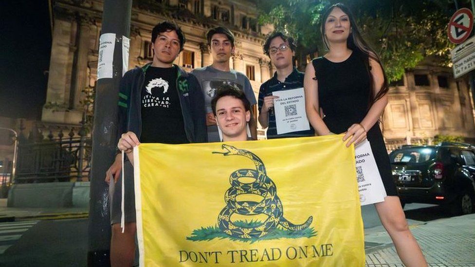 Members of the Pibes Libertarios group hold a Gadsden flag, a libertarian symbol that shows a snake and reads "Don't tread on me"