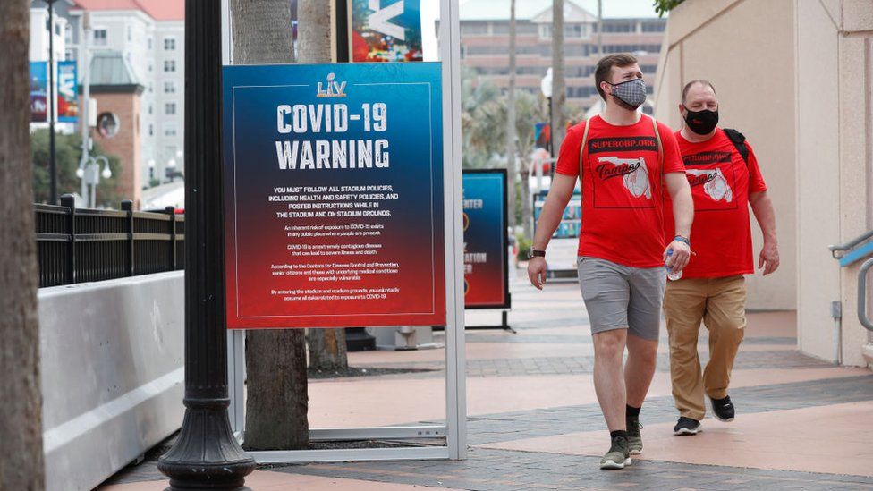 Two men walk by a Covid-19 warning sign in Florida