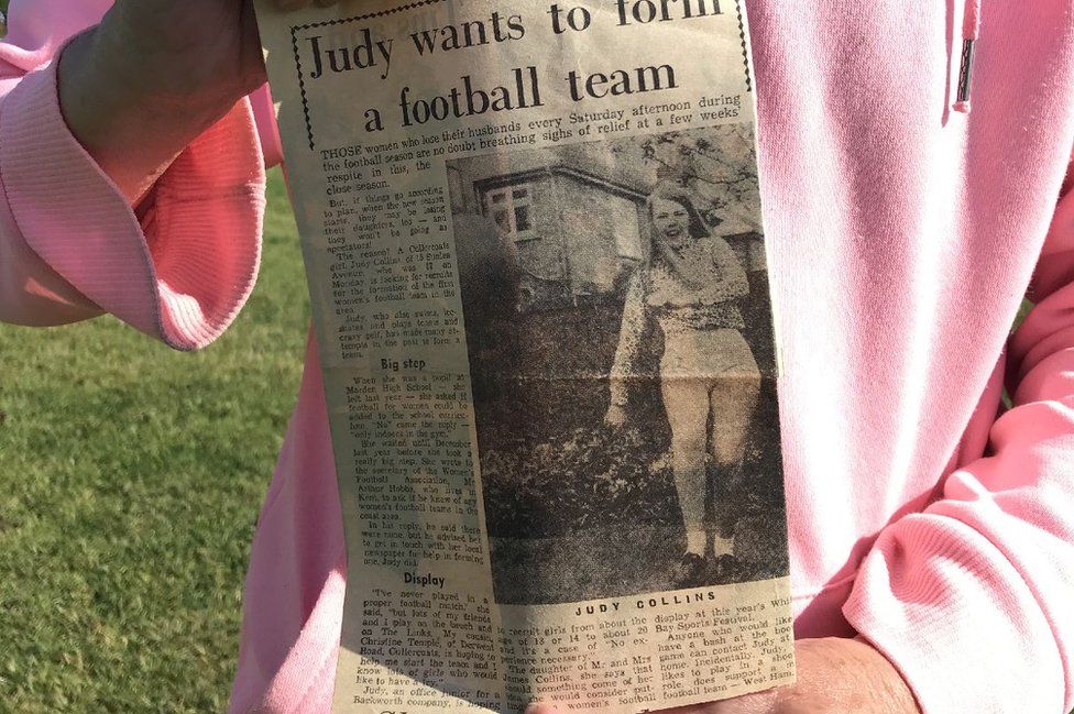 Judy Collins holds newspaper cutting from 1971 advertising her appeal for other footballers