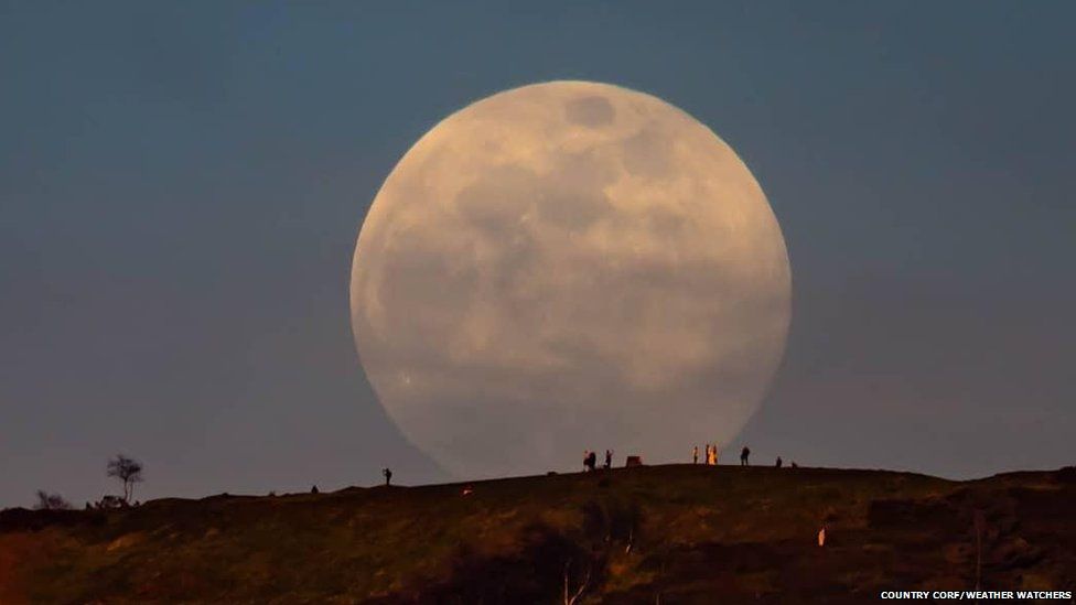 Large full moon rising over a hill
