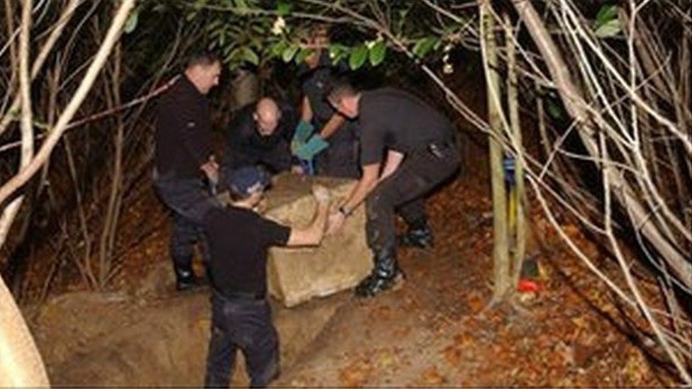 Police removing the box from the hole