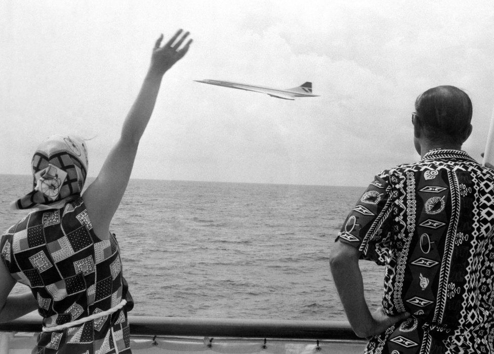 Queen Elizabeth II and the Duke of Edinburgh wave as Concorde flies by the Royal Yacht Britannia as the royal couple neared Barbados