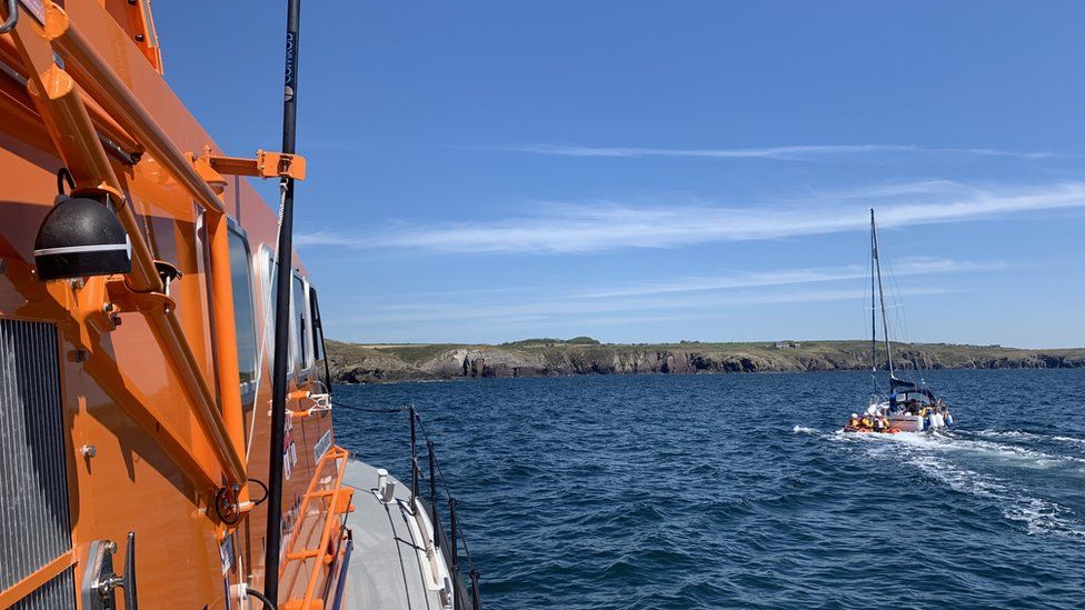 A stricken yacht being towed to safety by lifeboat