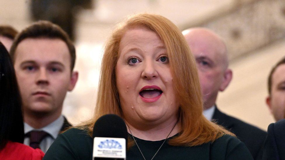 Naomi Long pictured speaking at a microphone