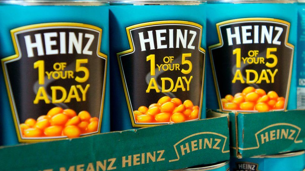 Банки с печеной фасолью Heinz на полке в магазине.