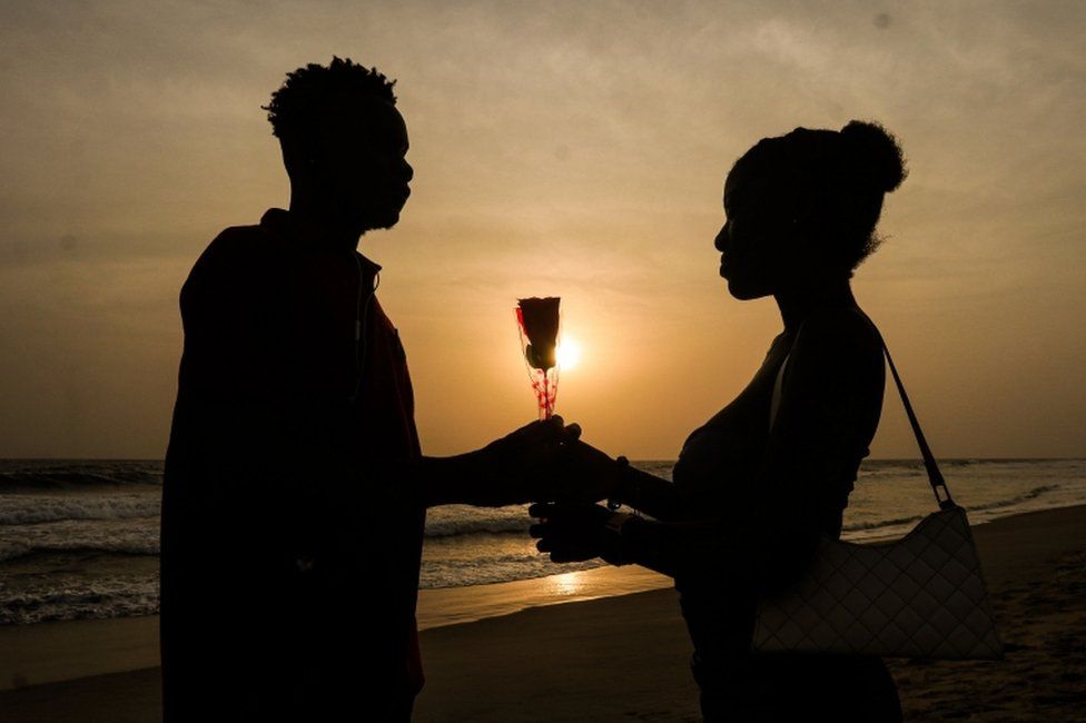 A couple hold a rose while watching the sunset on Sinkoe Beach in Monrovia, Liberia.