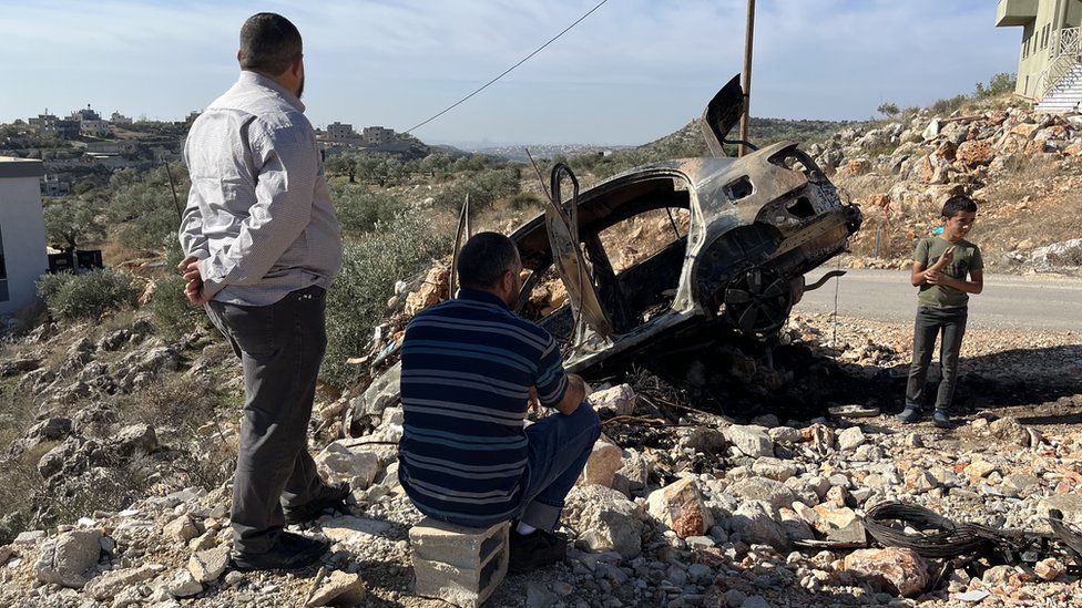 Palestinian men sit by side of road